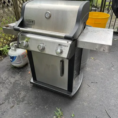 Sale Photo Thumbnail #67: Weber Spirit three-burner liquid propane gas grill in stainless steel and black, showing some outdoor wear and weathering.