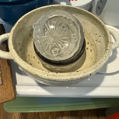 Sale Photo Thumbnail #279: Speckled ceramic colander with handles, holding a small cut glass bowl and a dark-rimmed glass dish.