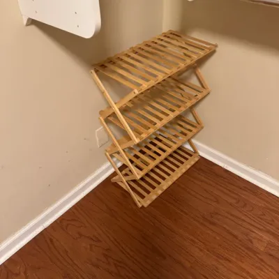 Sale Photo Thumbnail #139: Four-tier folding bamboo shoe rack, showing light wear, positioned in a closet corner.