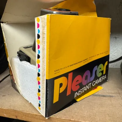 Sale Photo Thumbnail #101: Vintage Kodak Pleaser instant camera in its original, worn cardboard box with styrofoam packaging, circa late 1970s.