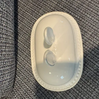 Sale Photo Thumbnail #259: Vintage white ceramic oval butter dish lid featuring a beaded rim and a dual-loop handle.