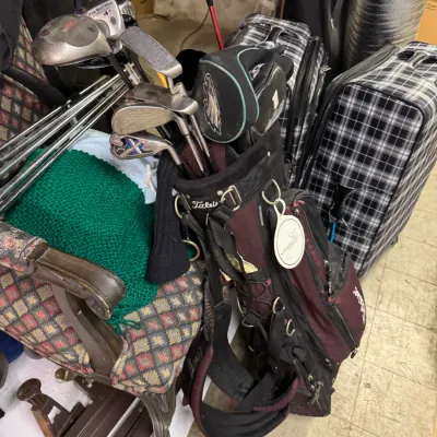 Sale Photo Thumbnail #108: Titleist golf bag in maroon and black, filled with an assortment of golf clubs including a Callaway Big Bertha driver and various irons.