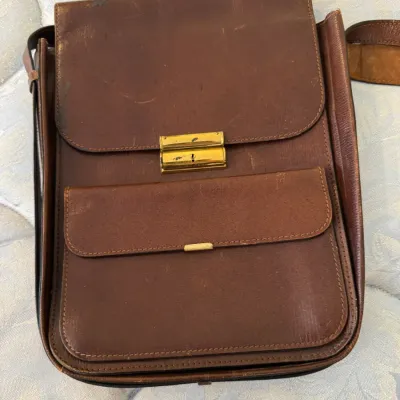 Sale Photo Thumbnail #46: Vintage brown leather messenger bag featuring a front pocket, gold-tone hardware, and a lockable clasp closure.