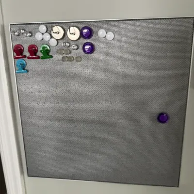 Sale Photo Thumbnail #330: Wall-mounted magnetic bulletin board with a textured silver-grey surface, featuring an assortment of colorful magnetic clips, hooks, and push-pin style magnets.