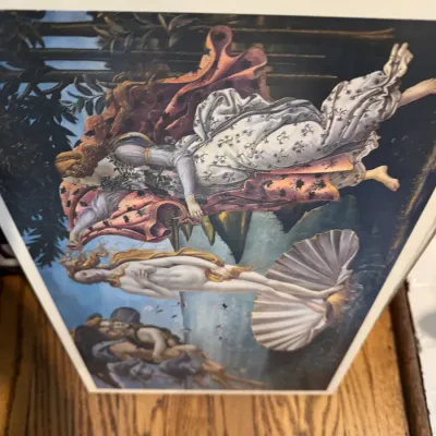 Sale Photo Thumbnail #250: Framed art print of Sandro Botticelli's "The Birth of Venus," displayed vertically on a wooden surface.