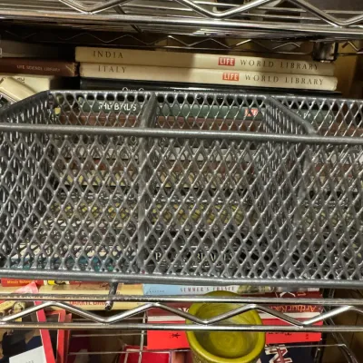 Sale Photo Thumbnail #122: Three-compartment silver mesh desk organizer sitting on a wire shelf in front of vintage books, including Life World Library volumes.