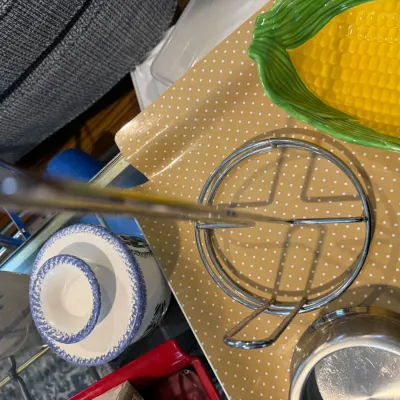 Sale Photo Thumbnail #307: Assorted kitchenware including a chrome metal stand, a yellow and green ceramic corn-on-the-cob dish, and blue and white speckled ceramic bowls.