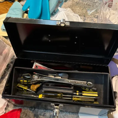 Sale Photo Thumbnail #238: Black metal toolbox with a removable tray, containing an assortment of hand tools including screwdrivers and an adjustable wrench.