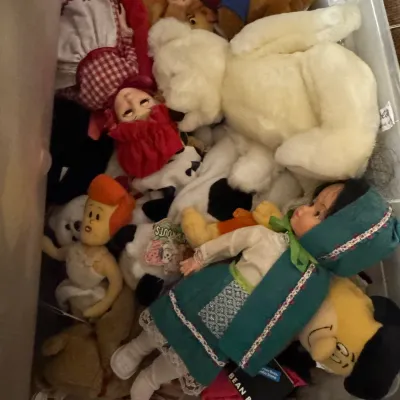Sale Photo Thumbnail #5: Assortment of vintage plush toys and dolls, including a large white teddy bear, a doll in a green dress, and various cartoon character figures, stored in a plastic bin.