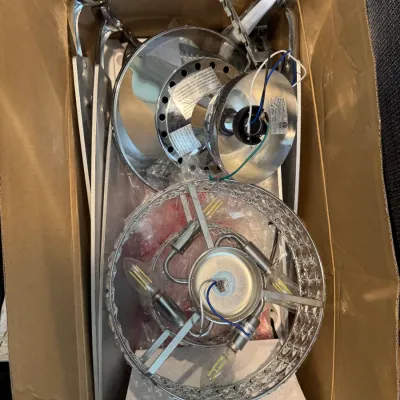 Sale Photo Thumbnail #274: Disassembled modern chrome and crystal-style ceiling fan with light fixture, packed in a cardboard box.