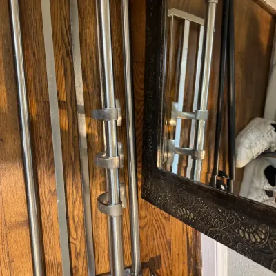 Sale Photo Thumbnail #272: Brushed nickel wall-mounted towel rack with an upper shelf and lower hanging bar, shown next to a dark-framed mirror.