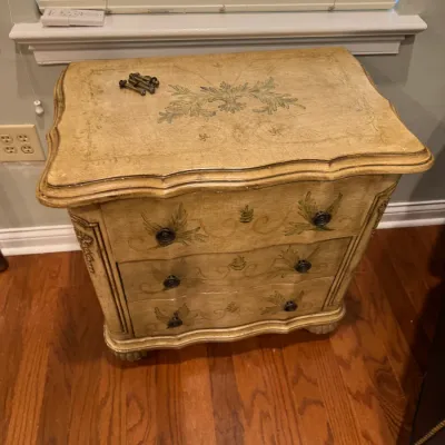 Sale Photo Thumbnail #141: Vintage French Provincial style three-drawer chest with a distressed cream finish, hand-painted green floral and scroll motifs, and a serpentine front.