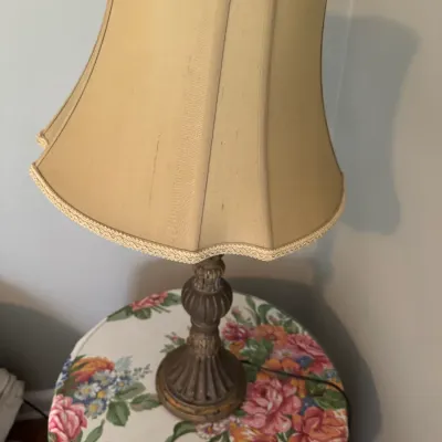 Sale Photo Thumbnail #205: Traditional table lamp with a carved, dark-finished baluster base and a bell-shaped beige fabric shade featuring braided trim.