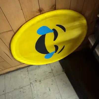 Sale Photo Thumbnail #151: Large yellow plastic snow sled featuring a laughing crying emoji graphic, showing light wear from use.