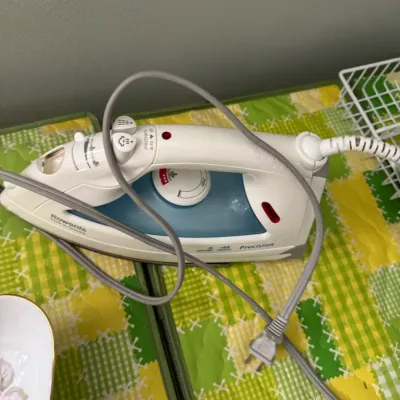 Sale Photo Thumbnail #323: Rowenta Precision steam iron with a white and blue plastic body, showing some light wear from use.