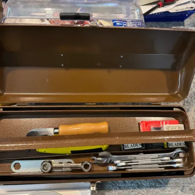 Sale Photo Thumbnail #237: Vintage brown metal cantilever toolbox containing various hand tools, including wrenches, utility knives, and replacement blades.