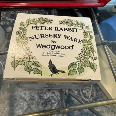 Sale Photo Thumbnail #265: Vintage Peter Rabbit Nursery Ware by Wedgwood in its original illustrated box, featuring Beatrix Potter designs.