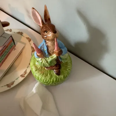 Sale Photo Thumbnail #52: Vintage Beswick Peter Rabbit porcelain figurine, depicting the character in his blue jacket holding carrots on a grassy base.