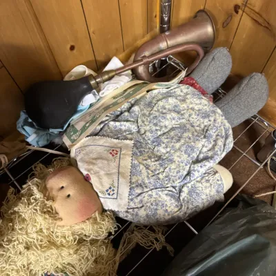 Sale Photo Thumbnail #126: Vintage handmade rag doll with yarn hair and a floral dress, resting on a wire shelf next to an antique brass bulb horn.
