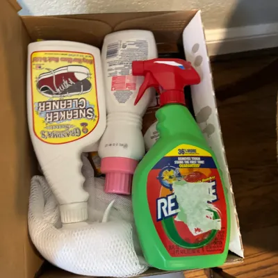 Sale Photo Thumbnail #273: Assorted household cleaning products, including Grandma's Secret Sneaker Cleaner and Resolve stain remover, stored in a cardboard box.