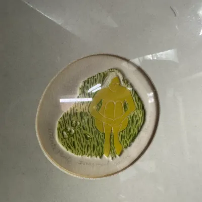 Sale Photo Thumbnail #10: Framed artist's proof print titled "Fragment" by Judith Shahn, featuring a stylized yellow figure seated in green grass within a circular mat opening.