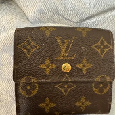 Sale Photo Thumbnail #31: Louis Vuitton monogram canvas compact wallet featuring a gold-tone snap closure, showing some wear along the edges.