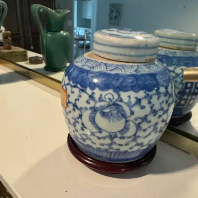 Sale Photo Thumbnail #258: Chinese blue and white porcelain ginger jar with floral motifs, complete with a matching lid and displayed on a dark wooden stand.