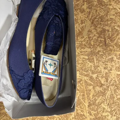 Sale Photo Thumbnail #92: Pair of navy blue fabric flat shoes with lace detailing on the toes, presented in their original box with tissue paper.