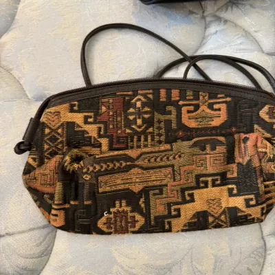 Sale Photo Thumbnail #166: Vintage woven tapestry shoulder bag featuring a geometric Southwestern-style pattern in earth tones, complete with a thin black strap and zipper closure.