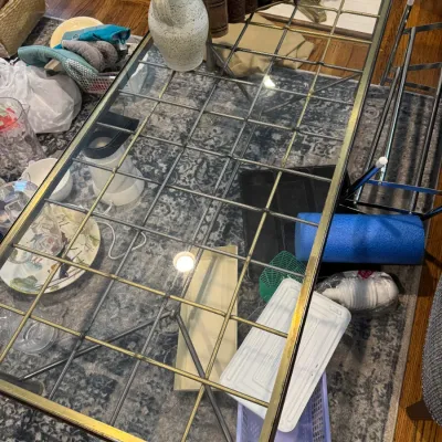 Sale Photo Thumbnail #268: Mid-century modern style brass and glass coffee table featuring a grid-patterned metal frame beneath the glass top, shown with various household items and decor.