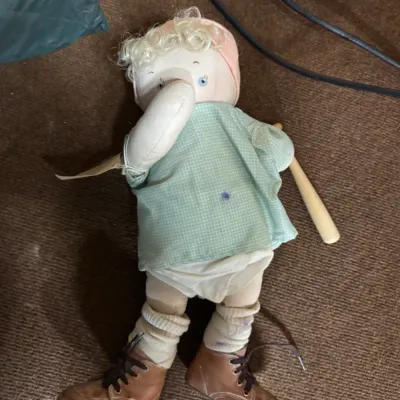 Sale Photo Thumbnail #125: Vintage handmade cloth doll featuring a baseball player theme, complete with a miniature wooden bat, leather shoes, and a green checkered shirt.