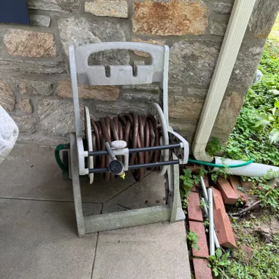 Sale Photo Thumbnail #312: Suncast plastic garden hose reel cart with a brown hose and spray nozzle, showing some outdoor wear.