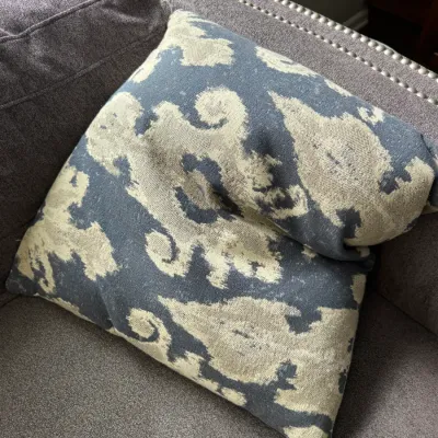 Sale Photo Thumbnail #315: Pair of square throw pillows featuring a blue and cream ikat-style damask pattern, resting on a gray upholstered sofa.
