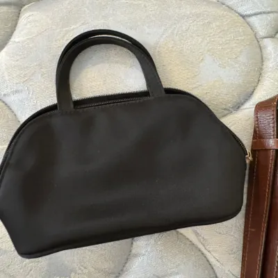 Sale Photo Thumbnail #165: Small black nylon handbag with dual top handles and a zippered closure, shown alongside a brown leather strap.