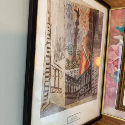 Sale Photo Thumbnail #235: Framed art print titled "Paseo de Colón" by Salvador Dalí, depicting a balcony view of the Columbus Monument in Barcelona, housed in a black frame with a white mat.