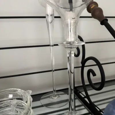 Sale Photo Thumbnail #351: Pair of elegant, tall clear glass candlestick holders with flared rims, displayed on a black wire shelf.