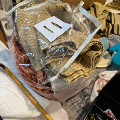 Sale Photo Thumbnail #240: Assorted household textiles, including a textured beige throw blanket, packaged in a clear zippered storage bag.