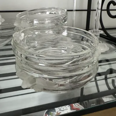 Sale Photo Thumbnail #347: Vintage Lalique-style clear glass bowls featuring frosted floral handles, displayed on a glass shelf.