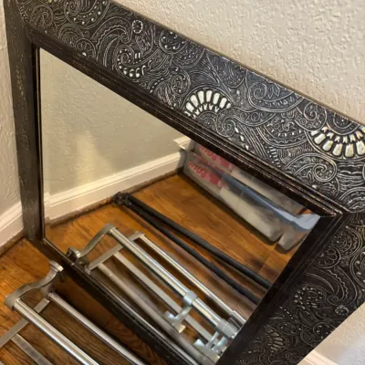 Sale Photo Thumbnail #270: Rectangular wall mirror featuring a wide, dark frame with an embossed silver paisley and scrollwork pattern.