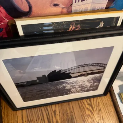 Sale Photo Thumbnail #249: Framed black and white photograph of the Sydney Opera House and Harbour Bridge, matted in white with a black frame.