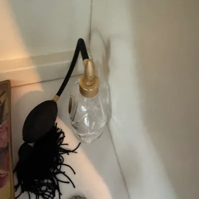 Sale Photo Thumbnail #180: Vintage clear cut-glass perfume bottle featuring a gold-tone collar and a black squeeze bulb atomizer with a decorative tassel.