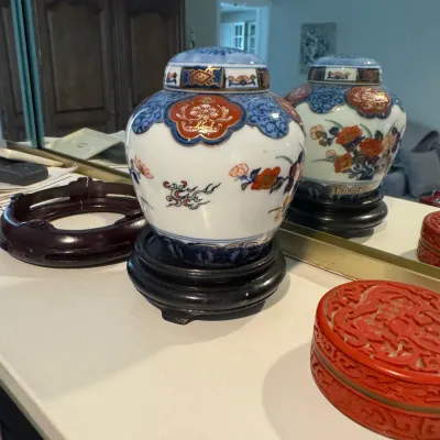 Sale Photo Thumbnail #255: Vintage Japanese Imari style porcelain ginger jar with lid, displayed on a black wooden stand alongside a carved red cinnabar-style box.