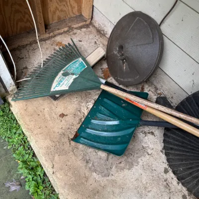 Sale Photo Thumbnail #75: Assorted outdoor tools including an Ames Green Sweeper plastic leaf rake, a green plastic snow shovel, and a round plastic umbrella base.