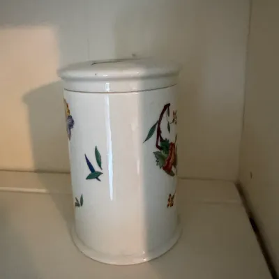 Sale Photo Thumbnail #187: Vintage white ceramic canister with a lid, featuring a colorful floral and botanical motif.