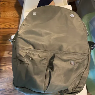 Sale Photo Thumbnail #282: Olive green nylon backpack featuring magnetic snap closures and a zippered main compartment, shown in gently used condition.
