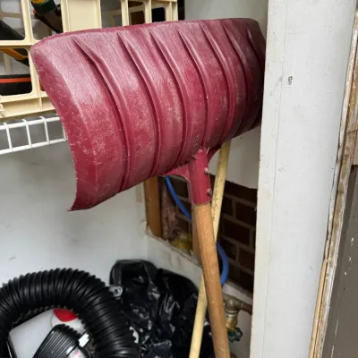 Sale Photo Thumbnail #69: Vintage red plastic snow shovel with a wooden handle, showing signs of wear from use.