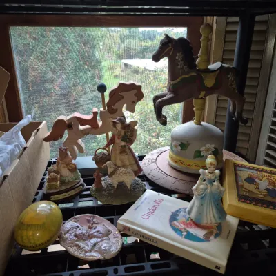Sale Photo Thumbnail #13: Collection of vintage decor items, including carousel horse figures, porcelain figurines, a Cinderella book and figurine, and decorative plaques.