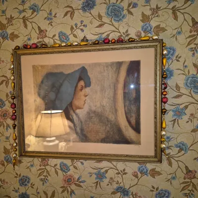 Sale Photo Thumbnail #64: Framed vintage art print featuring a profile portrait of a woman in a blue hat, adorned with a colorful beaded garland around the gold-tone frame.