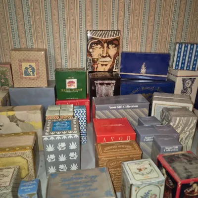 Sale Photo Thumbnail #5: Large collection of vintage Avon cosmetic and gift items in original packaging, including various decorative boxes and novelty items from the mid-to-late 20th century.