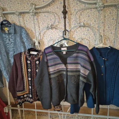 Sale Photo Thumbnail #11: Collection of women's vintage sweaters and jackets hanging on a white wrought iron bed frame, including items from Orvis and Woolrich.